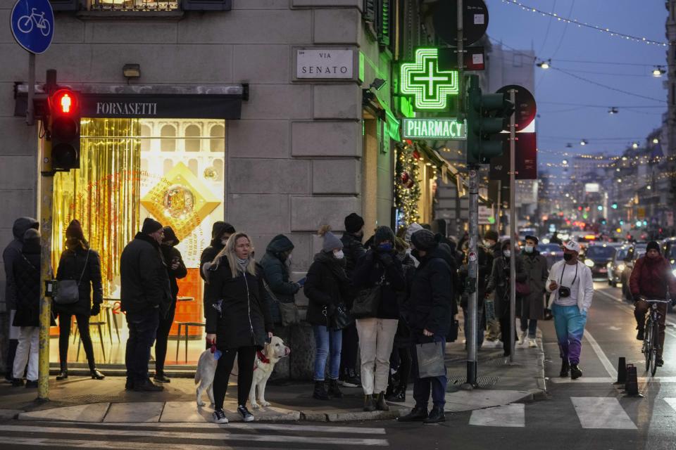 People line up outside a pharmacy for COVID-19 swab tests, in front of Milan's Duomo gothic cathedral, Italy, Thursday, Dec. 23, 2021. The Italian government is weighing possible outdoor mask mandates, increased testing and other measures to combat the new surge in infections fueled by the omicron variant. (AP Photo/Luca Bruno)