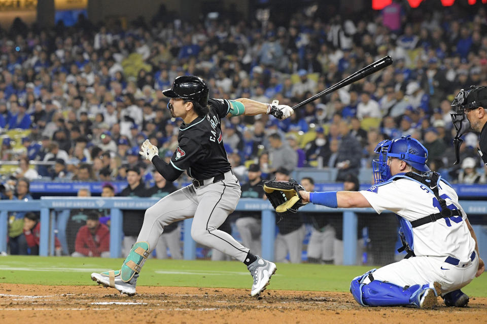 Arizona Diamondbacks' Corbin Carroll, left, hit a two RBI triple as Los Angeles Dodgers catcher Will Smith watches during the fifth inning of a baseball game Wednesday, May 22, 2024, in Los Angeles. (AP Photo/Mark J. Terrill)