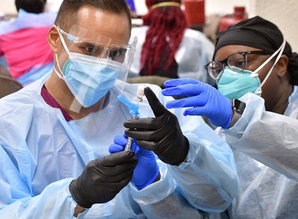 A registered nurse, at right, helps a nursing student prepare a dose of the COVID-19 vaccine. (Will Lester / Getty Images)