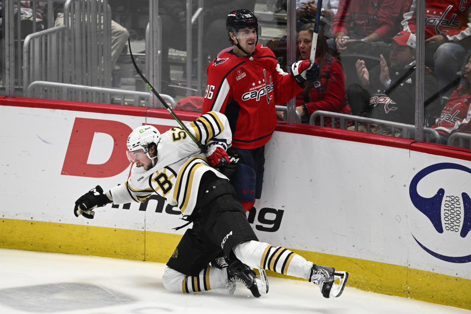 Boston Bruins defenseman Andrew Peeke (52) and Washington Capitals right wing Nicolas Aube-Kubel (96) battle along the boards during the third period of an NHL hockey game, Monday, April 15, 2024, in Washington. The Capitals won 2-0. (AP Photo/Nick Wass)