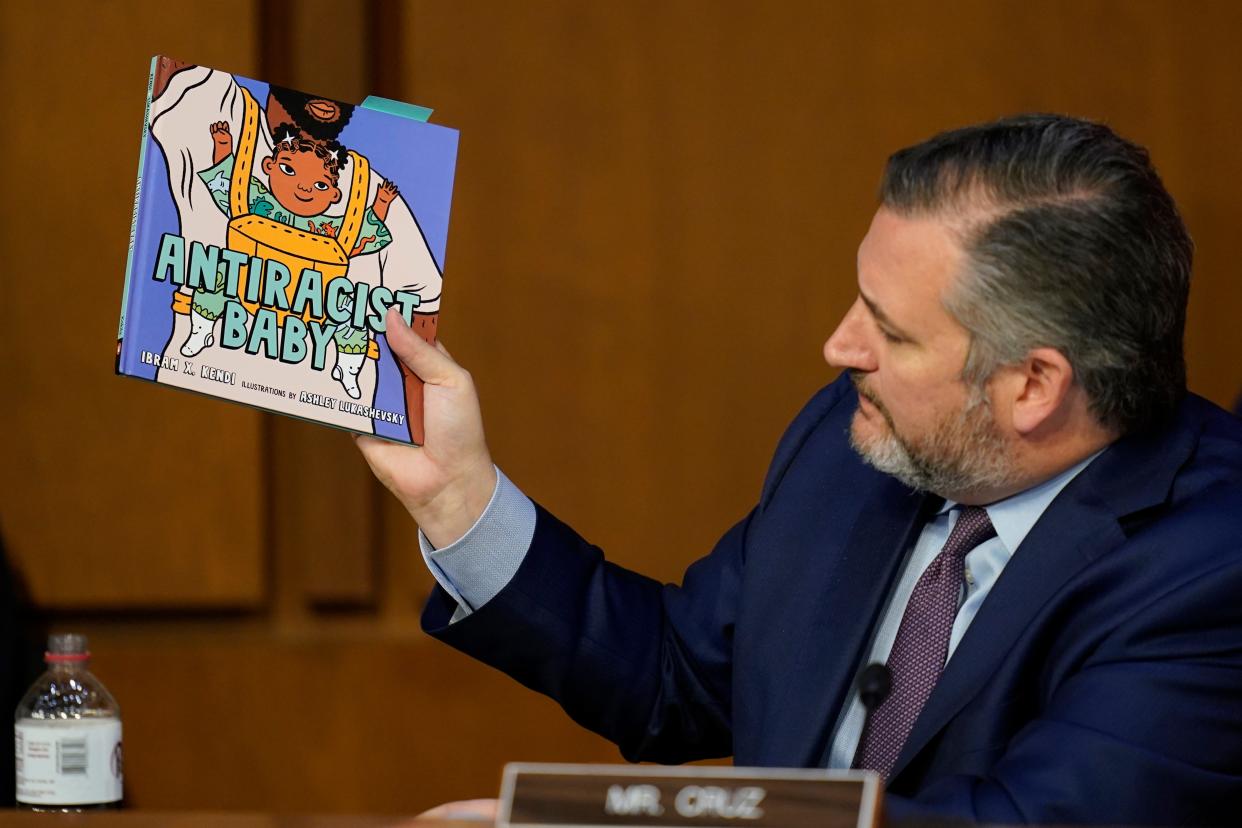 Senator Ted Cruz holding up a children's book in his right hand.