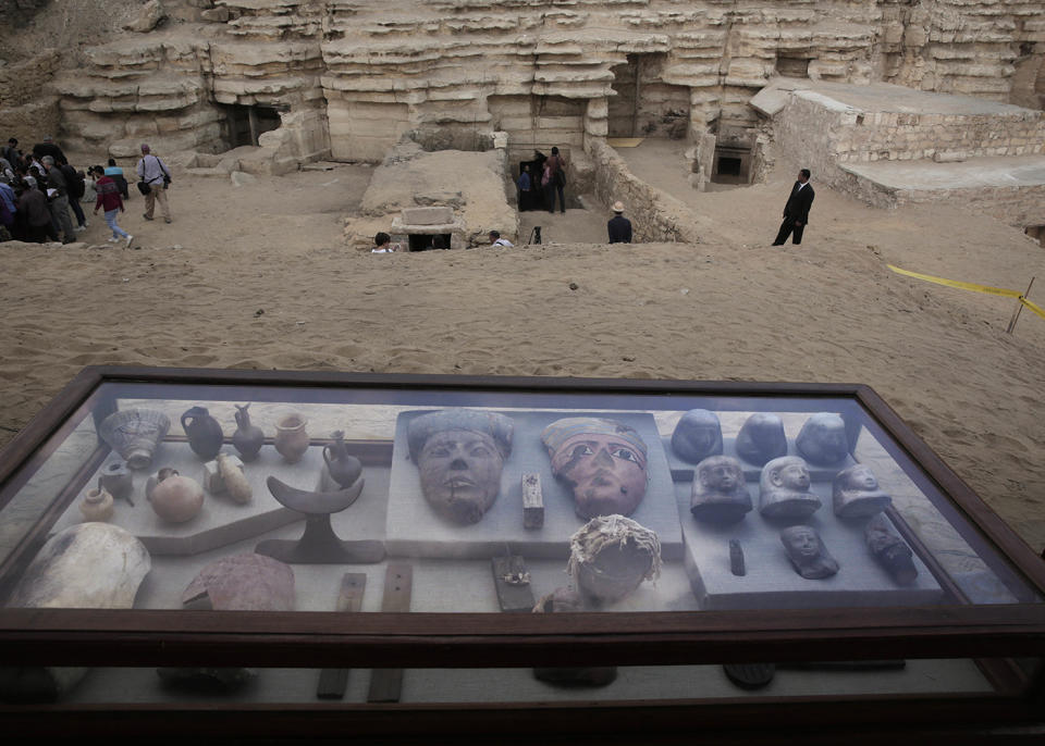 Artifacts on display in their glass case in front of newly discovered tombs, at an ancient necropolis near Egypt’s famed pyramids in Saqqara on Saturday. Source: AP Photo via AAP