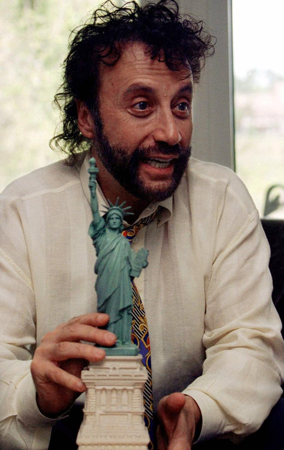 In this June 7, 2001 photo, comedian Yakov Smirnoff talks about his past 15 years as a U.S. citizen during an interview at his Branson theater. Smirnoff is holding the replica of the Statue of Liberty that he held when he was sworn in as a naturalized citizen on July 4, 1986. (AP Photo/John S. Stewart)