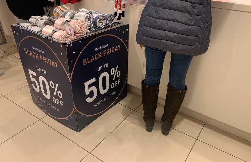 Customer stands next to a container advertising Black Friday offers in a branch of Mamas and Papas in Manchester