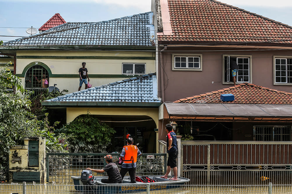 Flood victims wait on the roof of their home for assistance in Taman Sri Muda Section 25 Shah Alam December 20, 2021. — Picture by Hari Anggara