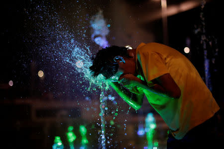 A Honduran boy, part of a caravan of thousands of migrants from Central America en route to the United States, plays with water fountains along the sidewalks of Tapachula city center, Mexico October 21, 2018. REUTERS/Ueslei Marcelino