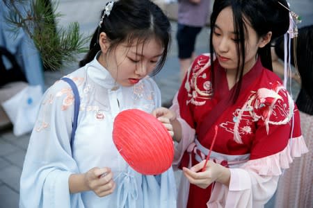 Girls dressed in "Hanfu" prepare for an event to mark the traditional Qixi festival, the Chinese equivalent of Valentine's Day, at a park in Beijing, China