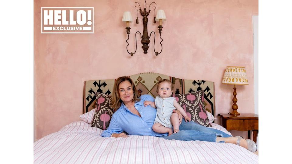 Penelope Chilvers posing on bed in pink bedroom at Cotswolds home