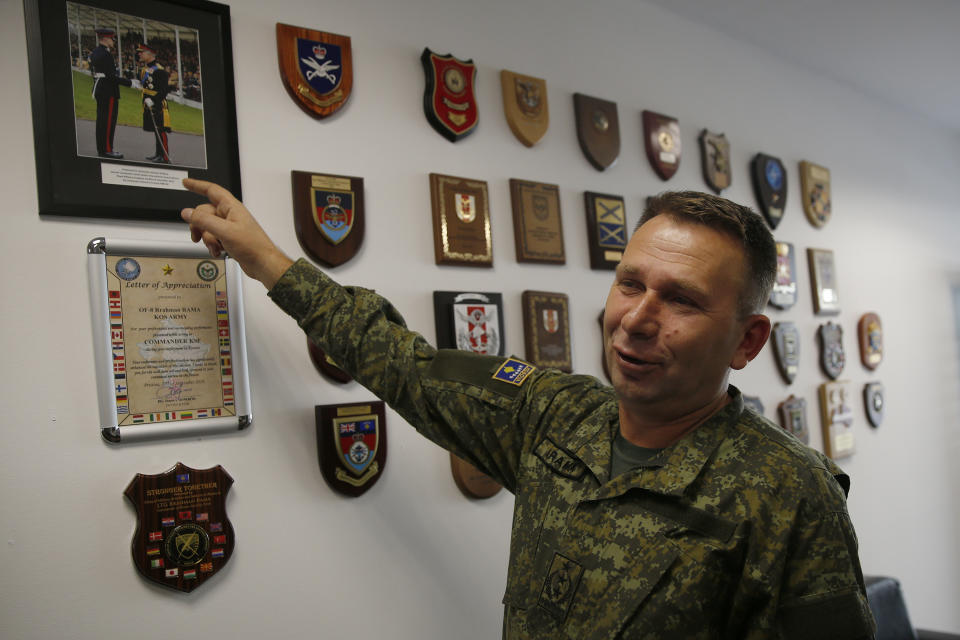 Commander of Kosovo Security Force Lt. Gen. Rrahman Rama shows a picture of KSF member Ismail Hoxha receiving a military award from Prince Charles during an interview with The Associated Press in capital Pristina, Kosovo on Thursday, Dec. 13, 2018, a day before the parliament votes to transform Kosovo Security Force into a regular army. Kosovo lawmakers are set to transform the Kosovo Security Force into a regular army, a move that significantly heightened tension with neighboring Serbia which even left open a possibility of an armed intervention in its former province. (AP Photo/Visar Kryeziu)