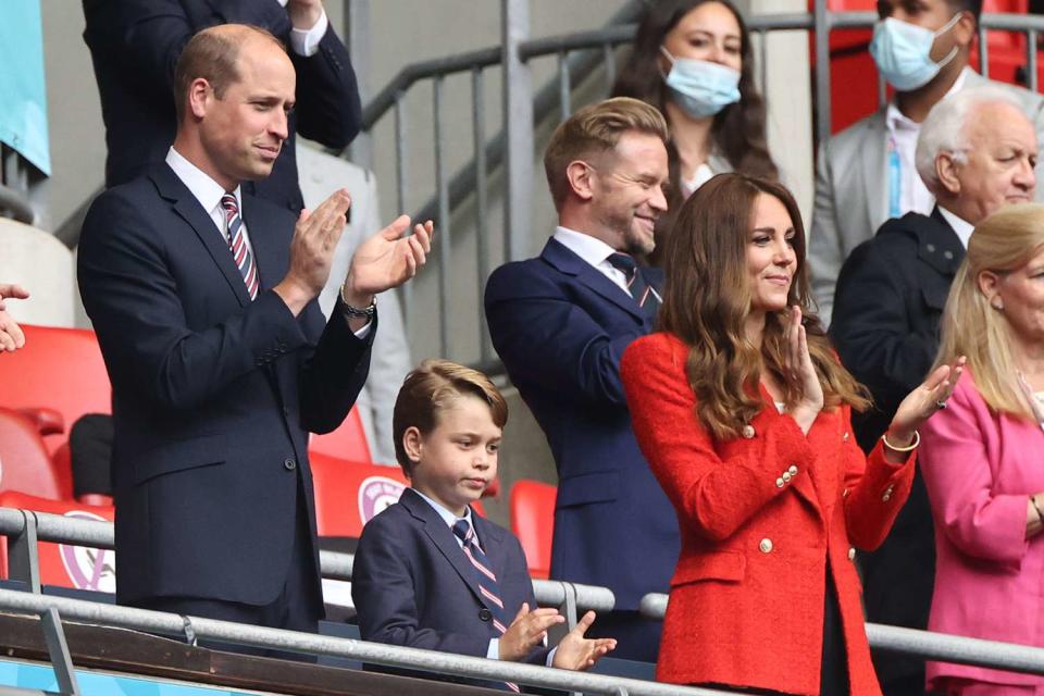 The British Prince William, Duke of Cambridge stands with his wife Kate, Duchess of Cambridge, and their son Prince George in the stands