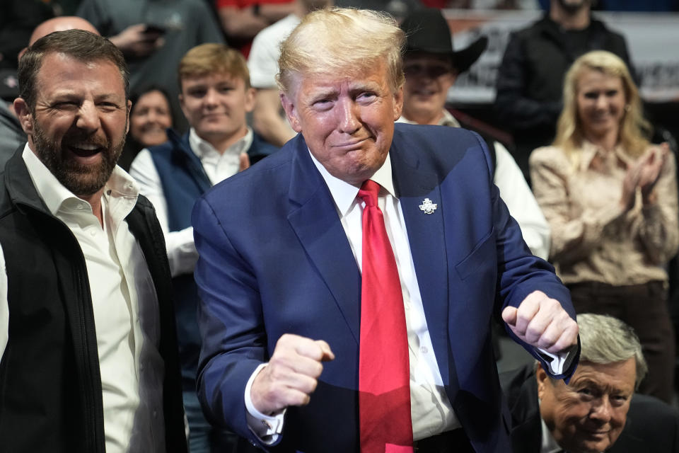 Former President Donald J. Trump gestures to Vito Arujau, NCAA wrestling champion at the 133 lb class, at the NCAA Wrestling Championships, Saturday, March 18, 2023, in Tulsa, Okla. At left if U.S. Sen. Markwayne Mullin. (AP Photo/Sue Ogrocki)