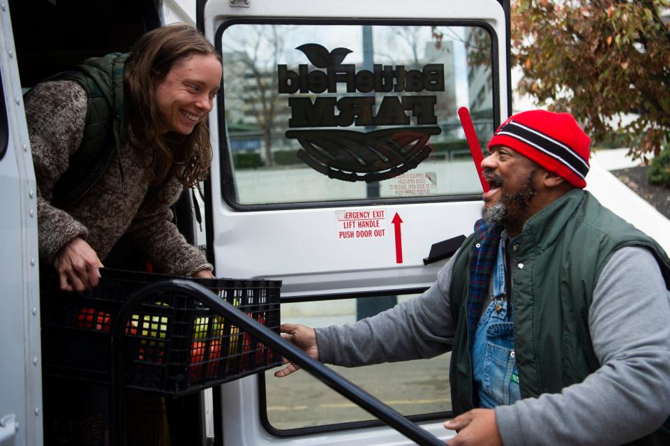 Volunteer Kat McGaha loads apple with Chris Battle into BattleField Farm’s veggie bus for distribution, after the farmer’s market in Market Square, Wednesday, Nov. 16, 2022.