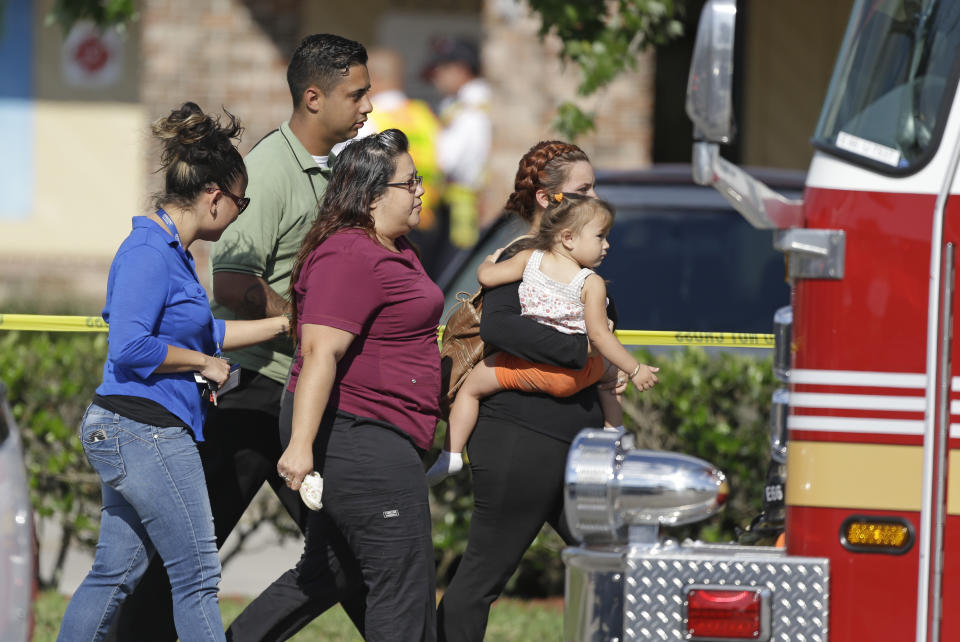 Parents and relatives leave a day care center with their children after a vehicle crashed into the center, Wednesday, April 9, 2014, in Winter Park, Fla. At least 15 people were injured, including children. (AP Photo/John Raoux)