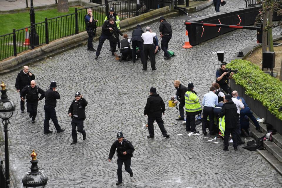 Police and paramedics treat a wounded man at the scene in the grounds of Parliament (Stefan Rousseau/PA)