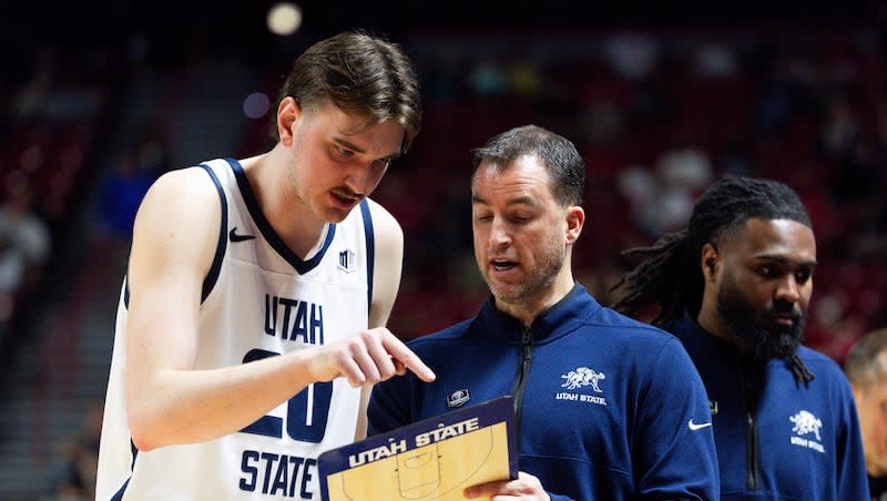 Utah State Aggies coach Danny Sprinkle talks to Aggies center Isaac Johnson (20) during the game between the Utah State and the Fresno State in the quarterfinals of the Mountain West tournament at the Thomas & Mack Center in Las Vegas on Thursday, March 14, 2024.