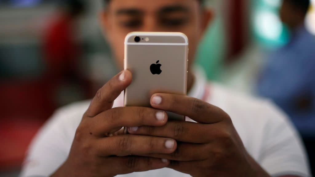 A salesman checks a customer's iPhone at a mobile phone store in New Delhi