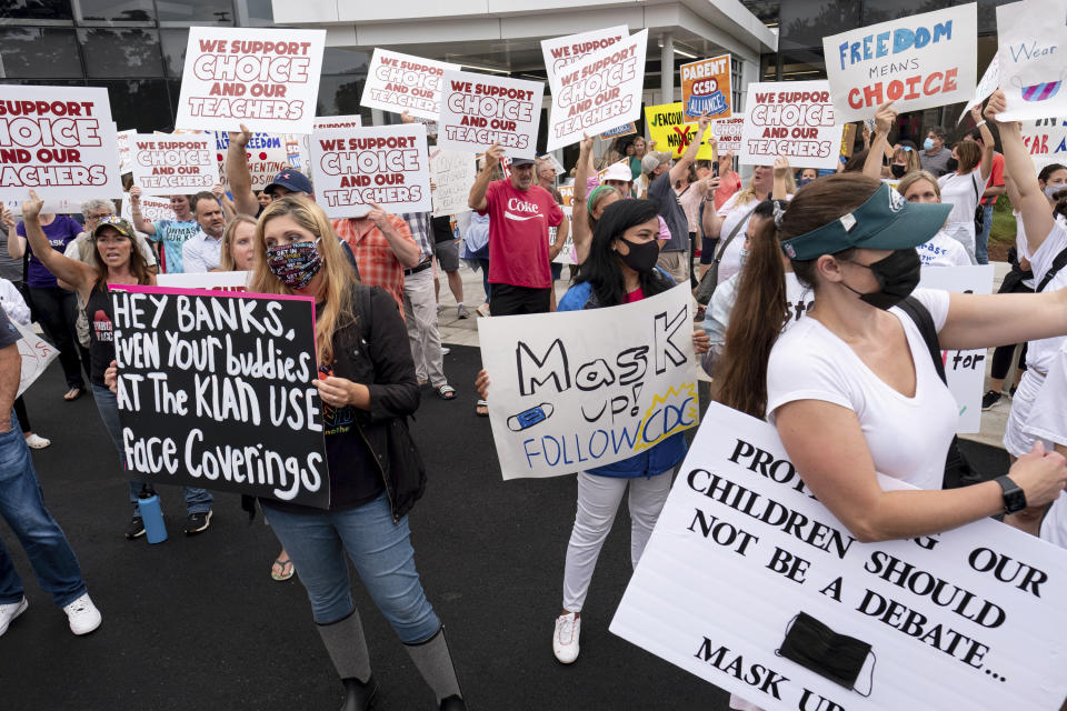 FILE - In this Aug. 19, 2021, file photo, people in favor of and against a mask mandate for Cobb County schools gather and protest ahead of the school board meeting, in Marietta, Ga. A growing number of school board members across the U.S. are resigning or questioning their willingness to serve as meetings have devolved into shouting contests over contentious issues including masks in schools. (Ben Gray/Atlanta Journal-Constitution via AP, File)