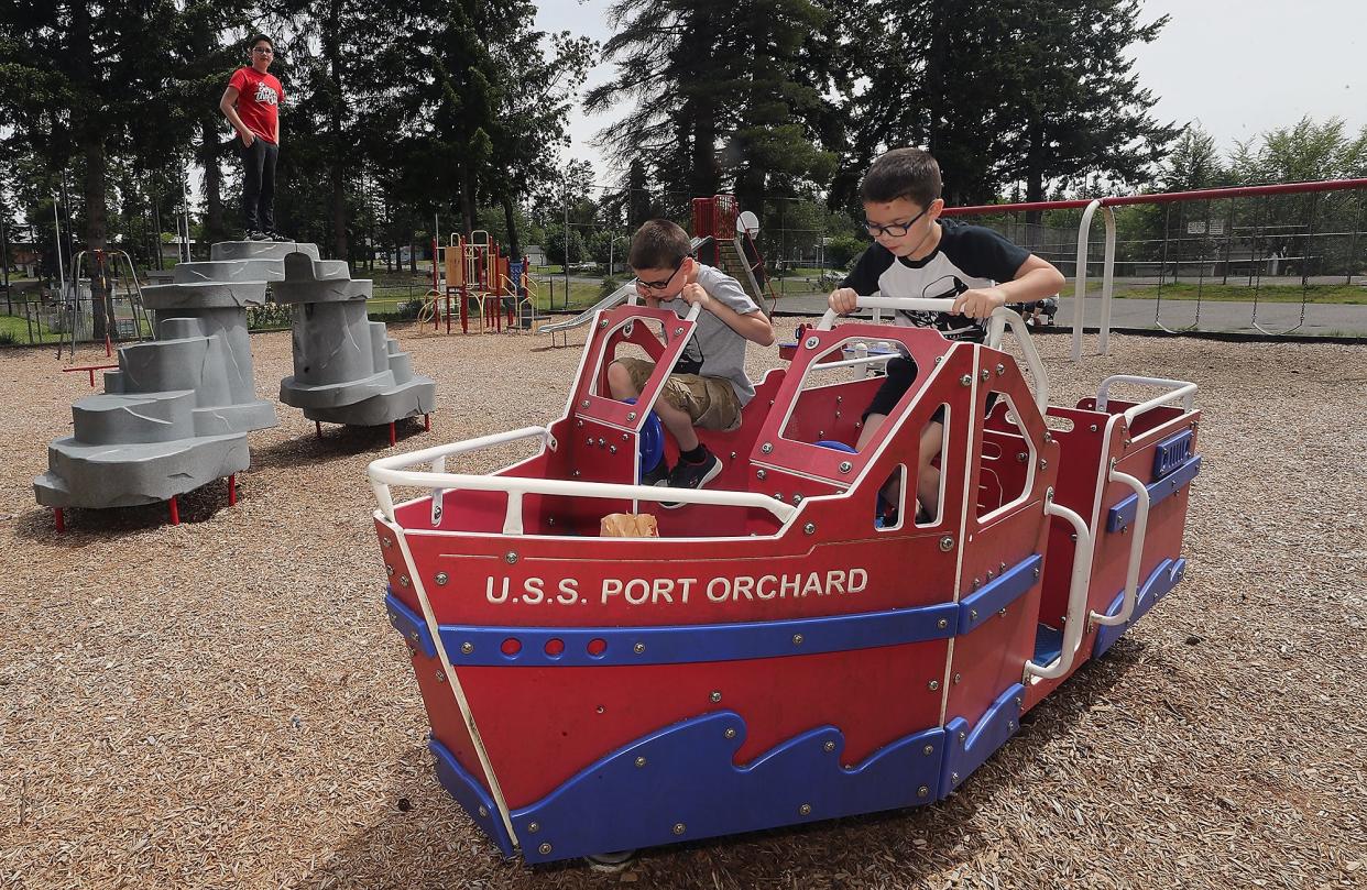 Henry Young, 10, center, and his brother Calvin, 7, right, pretend to drive the USS Port Orchard playground boat with their knees as their older brother Jack, 13, stands atop another play structure at Givens Park in Port Orchard on Wednesday. City staff are proposing increasing the impact fees that developers pay to help build and maintain parks in the city.