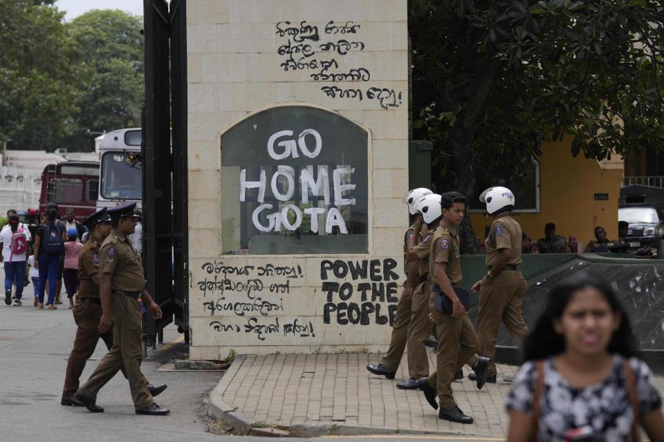 Police officers and people walk past a vandalised entrance to the president's official residence in Colombo, Sri Lanka, Sunday, July 10, 2022. Sri Lanka’s opposition political parties will meet Sunday to agree on a new government a day after the country’s president and prime minister offered to resign in the country’s most chaotic day in months of political turmoil, with protesters storming both officials’ homes and setting fire to one of the buildings in a rage over the nation’s economic crisis.. (AP Photo/Eranga Jayawardena)