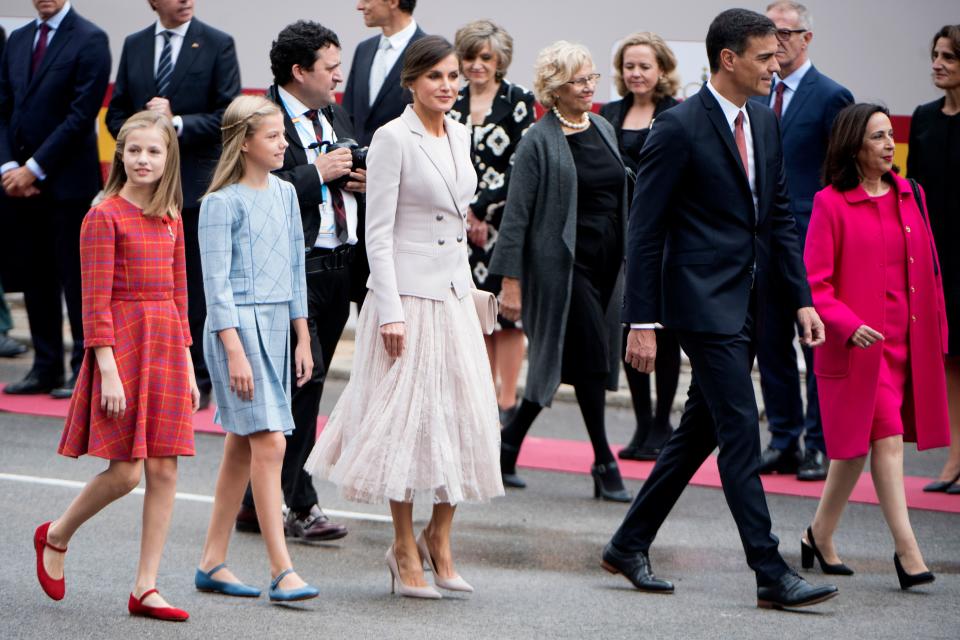 Las nietas de Juan Carlos I apostaron por el estampado de cuadros en 2018. La primera en la línea de sucesión al trono español llevó un conjunto en tonos naranjas, mientras que la infanta vistió de azul. Letizia y sus hijas desfilaron junto a Pedro Sánchez, que fue elegido presidente ese año. (Foto: Curto de la Torre / AFP / Getty Images)