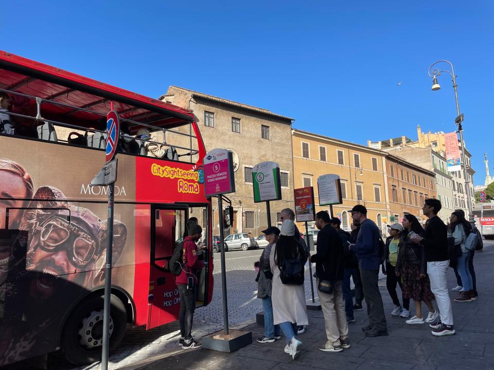 people lining up for a hop on hop off bus in rome, italy