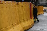 Man wearing a face mask walks by barricades set up at a residential area in Wuhan