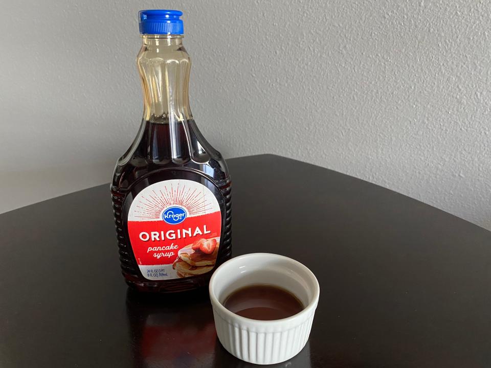 bottle of kroger pancake syrup next to a white ramekin filled with the syrup