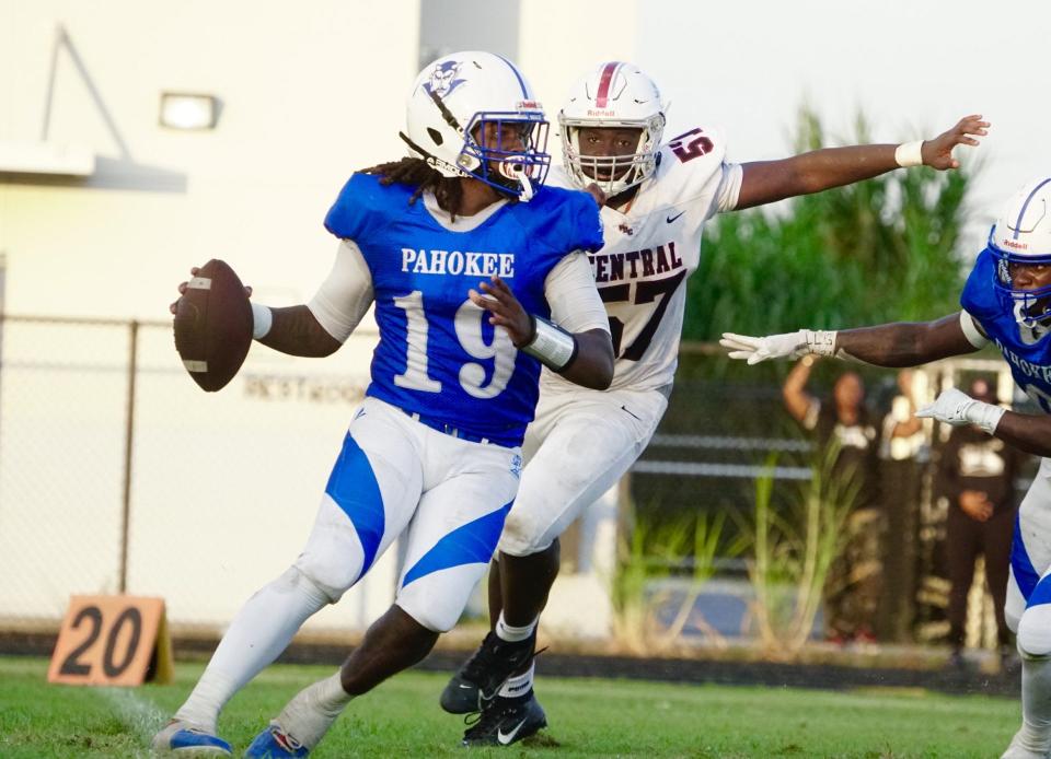 Palm Beach Central junior Brian Simon (57) gives chase to Pahokee quarterback JayJay Boyd (19) in a game on Thursday, Sept. 14, 2023 in Pahokee.