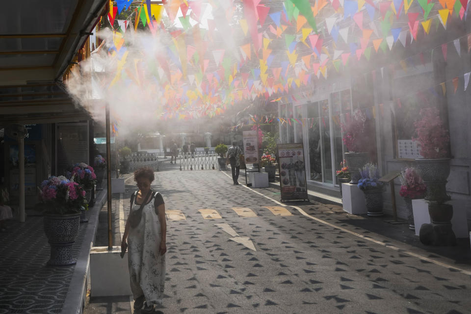 FILE - A woman walks through spay water for cooling down from hot temperatures in Bangkok, Thailand, on April 9, 2024. Southeast Asia is coping with a weekslong heat wave as record-high temperatures have led to school closings in several countries and urgent health warnings throughout the region. (AP Photo/Sakchai Lalit, File)