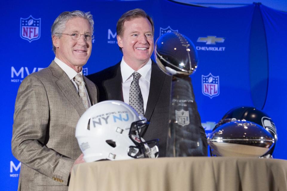 Roger Goodell, commissioner of the National Football League, center, and Pete Carroll, head coach of the Seattle Seahawks, pose for a photograph beside the Vince Lombardi and MVP trophy during a news conference at the Super Bowl XLVIII Media Center at the Sheraton hotel, Monday, Feb. 3, 2014, in New York. The Seattle Seahawks defeated the Denver Broncos, 43-8. (AP Photo/John Minchillo)