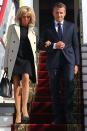 <p>Arriving in Russia wearing a black sheath dress and cream trench coat.</p>