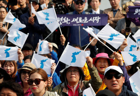 FILE PHOTO: People hold the Korean unification flag as they watch a news report on the inter-Korean summit, near the demilitarized zone separating the two Koreas, in Paju, South Korea, April 27, 2018. REUTERS/Kim Hong-ji/File Photo