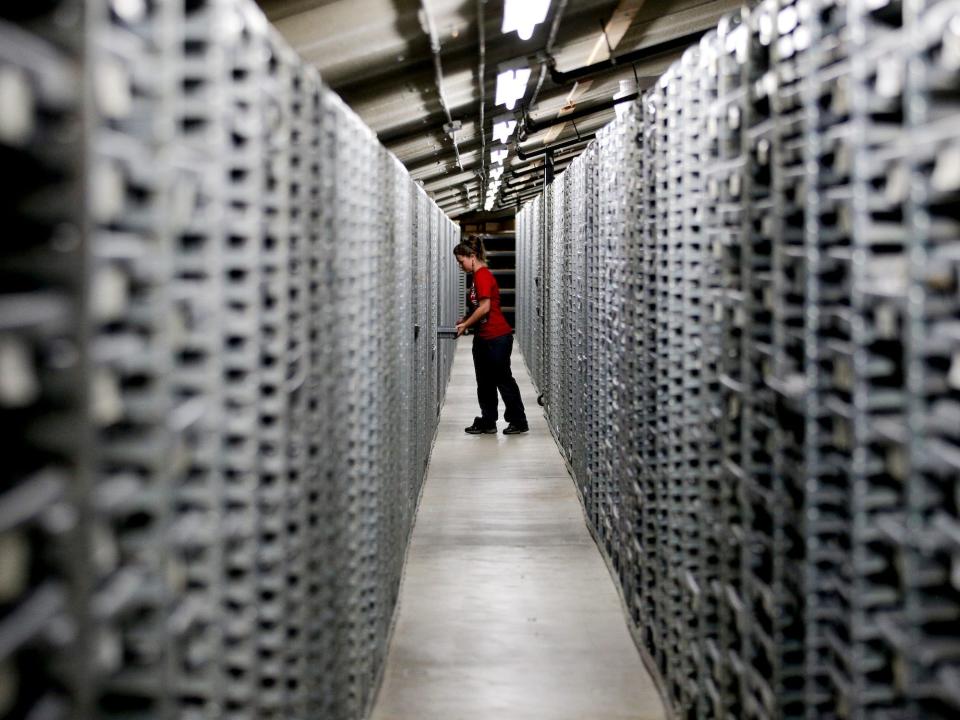 Ashely Farrell pulls a drawer filled with fossils in a long corridor of sample shelves at the paleontological lab at the George C. Page Museum at the La Brea Tar Pits