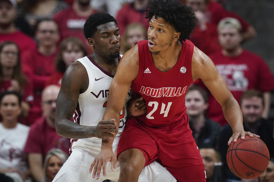 Louisville forward Dwayne Sutton (24) plays against Virginia Tech guard Tyrece Radford (23) during the first half of an NCAA college basketball game, Sunday, March 1, 2020, in Louisville, Ky. (AP Photo/Bryan Woolston)