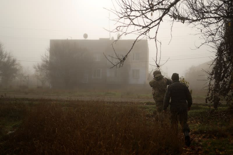 Ukrainian serviceman walks with a chaplain on a street in a village near Shihurivka