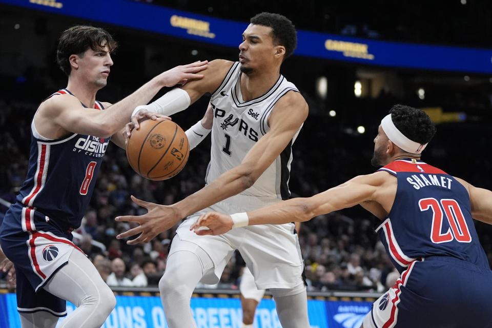 San Antonio Spurs center Victor Wembanyama (1) looks to pass around Washington Wizards forward Deni Avdija (8) and guard Landry Shamet (20) during the first half of an NBA basketball game Saturday, Jan. 20, 2024, in Washington. (AP Photo/Mark Schiefelbein)