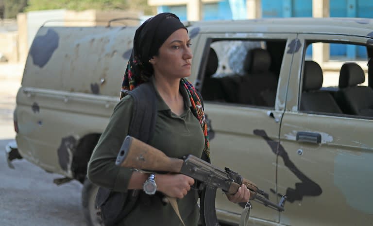 A member of the Kurdish security forces walks past a bullet-riddled Syrian government pick-up truck in the northeastern city of Qamishli where clashes killed 18 combatants on September 8, 2018