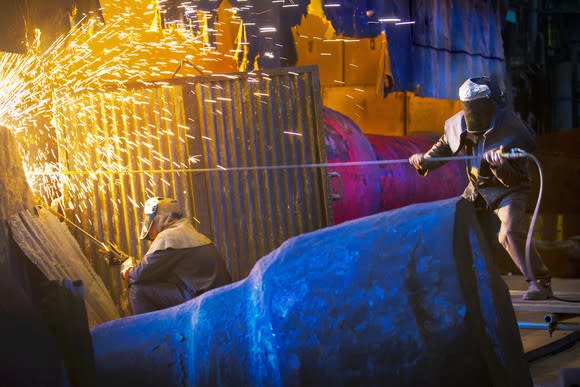 Two men working in a steel mill with sparks flying