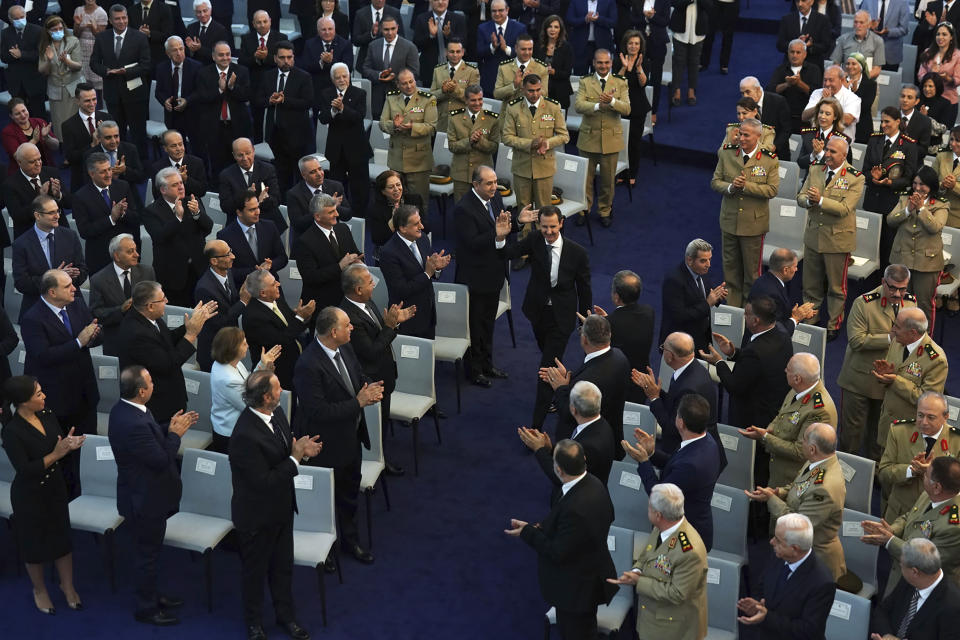 In this photo released by the official Facebook page of the Syrian Presidency, Syrian President Bashar Assad, center, waves to his supporters upon arrival to takes the oath of office for a fourth seven-year term, at the Syrian Presidential Palace in the capital Damascus, Syria, Saturday, July 17, 2021. In power since 2000, Assad's re-election in a landslide was not in doubt. His new term starts with the country still devastated by the 10-year war and sliding deeper into a worsening economic crisis. (Syrian Presidency via Facebook via AP)