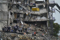 FILE - Search and rescue personnel work atop the rubble at the Champlain Towers South condo building, where scores of people remain missing after it partially collapsed the week before June 30, 2021, in Surfside, Fla. Friday, June 24, 2022, marks the anniversary of the oceanfront condo building collapse that killed 98 people in Surfside, Florida. The 12-story tower came down with a thunderous roar and left a giant pile of rubble in one of the deadliest collapses in U.S. history. (AP Photo/Lynne Sladky, File)