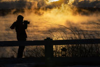 Kim Hunt of Cumberland, Maine, photographs arctic sea smoke on the coast of South Portland, Maine, Saturday, Feb. 4, 2023. The morning temperature was about -10 degrees Fahrenheit. (AP Photo/Robert F. Bukaty)