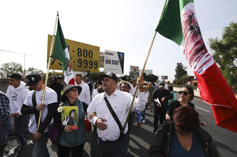 Julian LeBaron carries a Mexican flag during a protest against violence called "Walk for Peace" as the group leaves Cuernavaca, Mexico, Thursday, Jan. 23, 2020, with Mexico City as their destination. Activist and poet Javier Sicilia is leading his second march against violence in Mexico, this time accompanied by members of the LeBaron family, and plan to reach Mexico's National Palace on Sunday. (AP Photo/Eduardo Verdugo)