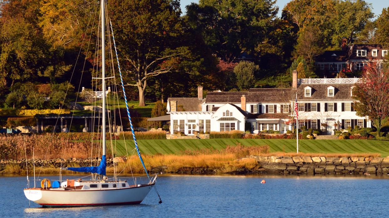 Greenwich, CT, USA October 27, 2013 A sailboat is moored just off shore of a Luxury Waterfront Home in Greenwich, Connecticut.