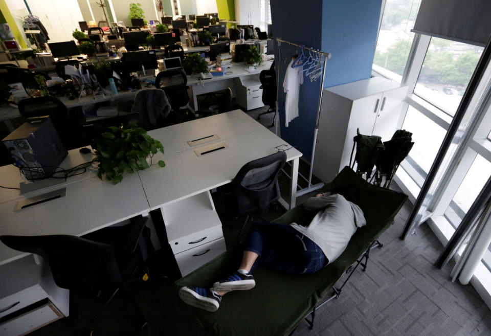 Kou Meng, product manager of RenRen Credit Management Co. in Beijing, sleeps on a camp bed at the office early in the morning on April 27, 2016. (Jason Lee/Reuters)