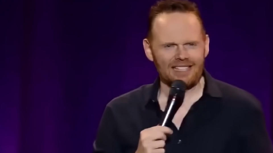 Bill Burr smiling with a microphone in his hand