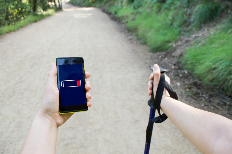 A hiker with a phone showing a low battery