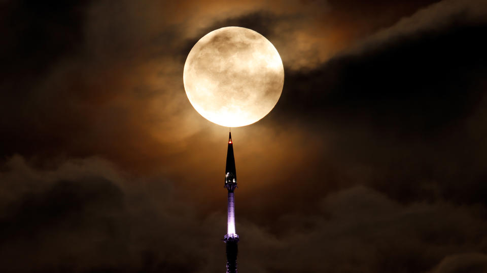 Full Super Flower Moon rises behind the antenna on top of One World Trade Center in New York City.