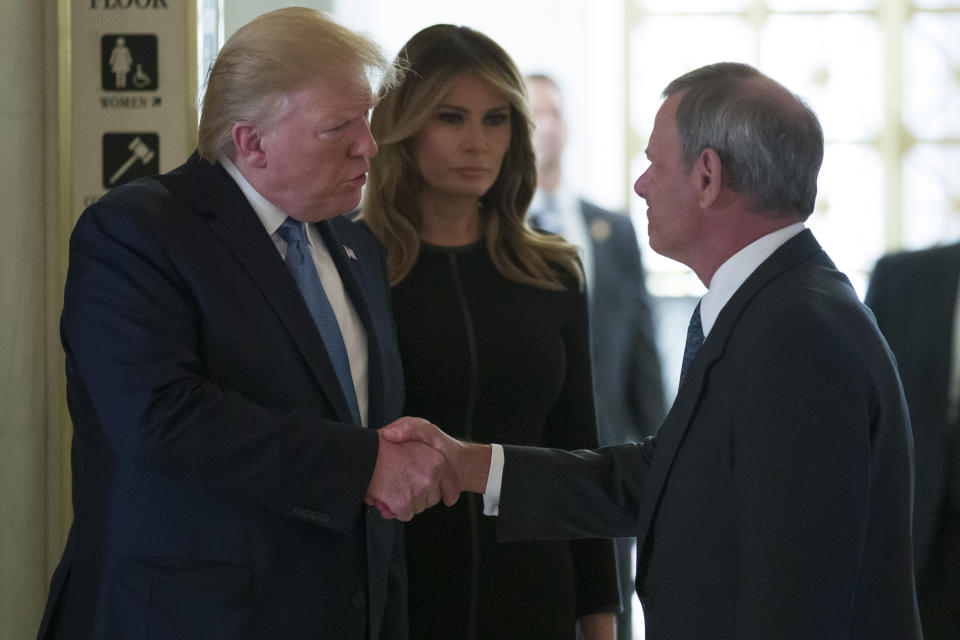 President Donald Trump, left, shakes hands with Supreme Court Chief Justice John Roberts, accompanied by first lady Melania Trump, as they arrive to view the casket of Justice John Paul Stevens at the Supreme Court, Monday, July 22, 2019, in Washington. (AP Photo/Alex Brandon)