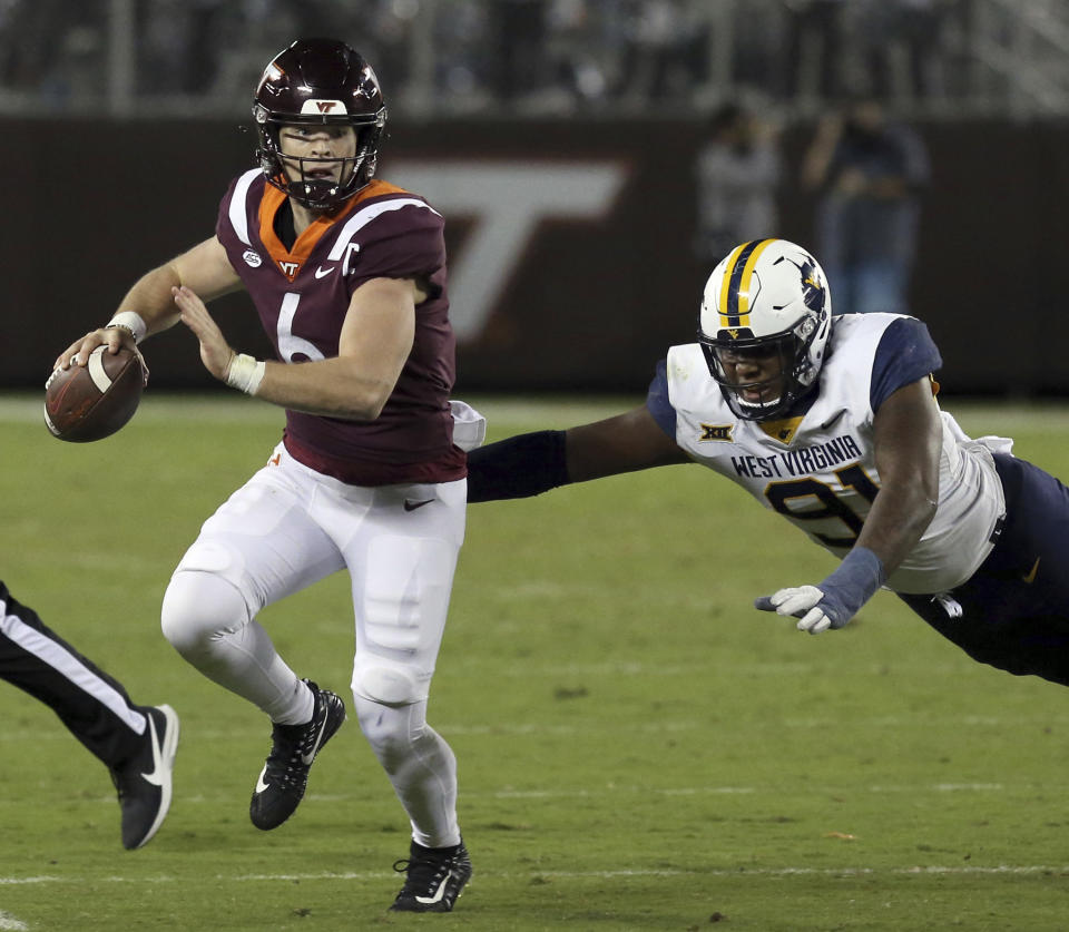 Virginia Tech's Virginia Tech's quarterback Grant Wells (6) attempts to elude West Virginia defensive lineman Sean Martin (91) in the second half of the West Virginia-Virginia Tech NCAA college football game in Blacksburg Va. Thursday September 22 2022. (Matt Gentry/The Roanoke Times via AP)