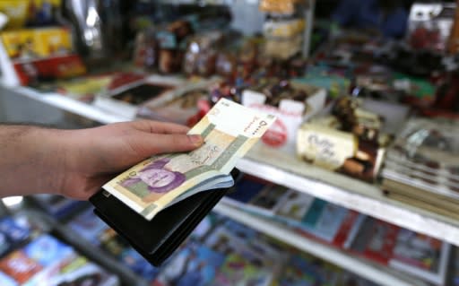 An Iranian holds a large wad of rials at the till in a Tehran store on July 31, 2018, as the currency hits a fresh record-low of 119,000 to the dollar